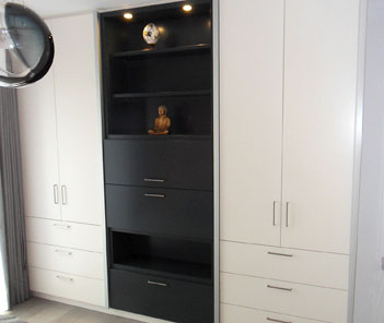 ein Kleiderschrank aus weiß lackiertem Holz, in der Mitte befindet sich eine dunkle Glasscheibentür