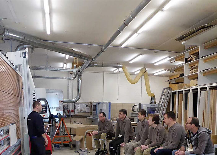 DAs Personal der Firma L&K Tischlerei posiert vor dem Heck eines Firmenfahrzeugs